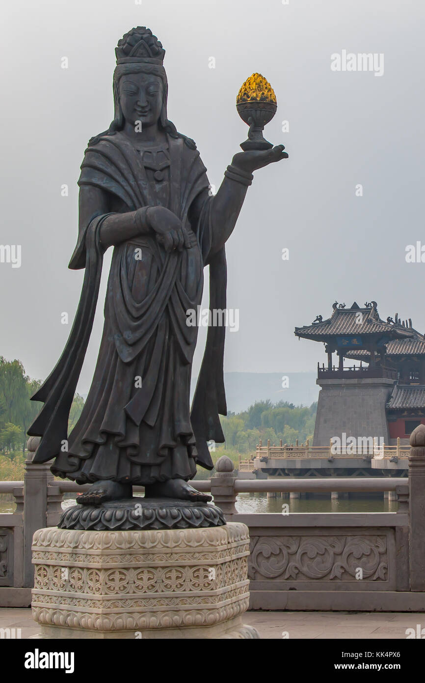 Ein grosser Stein geschnitzte Statue eines buddhistischen diety Holding eine goldene Objekt. Stockfoto