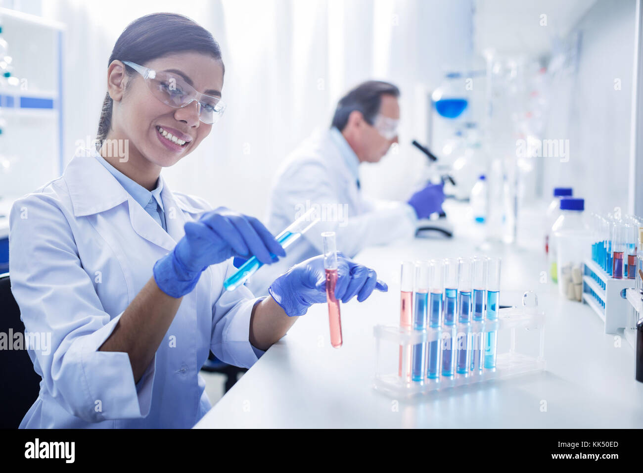 Freudige positive Frau arbeiten mit chemischen Reagenzien Stockfoto