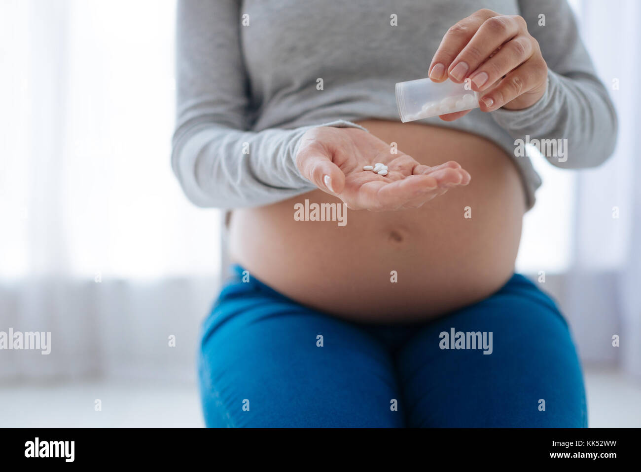 Magic Vitamine. selektive Fokus der schwangeren Frau, die Hände, die die Vitamin Pillen, indem Sie es von transparent Flasche im Palm beim Sitzen ein Stockfoto