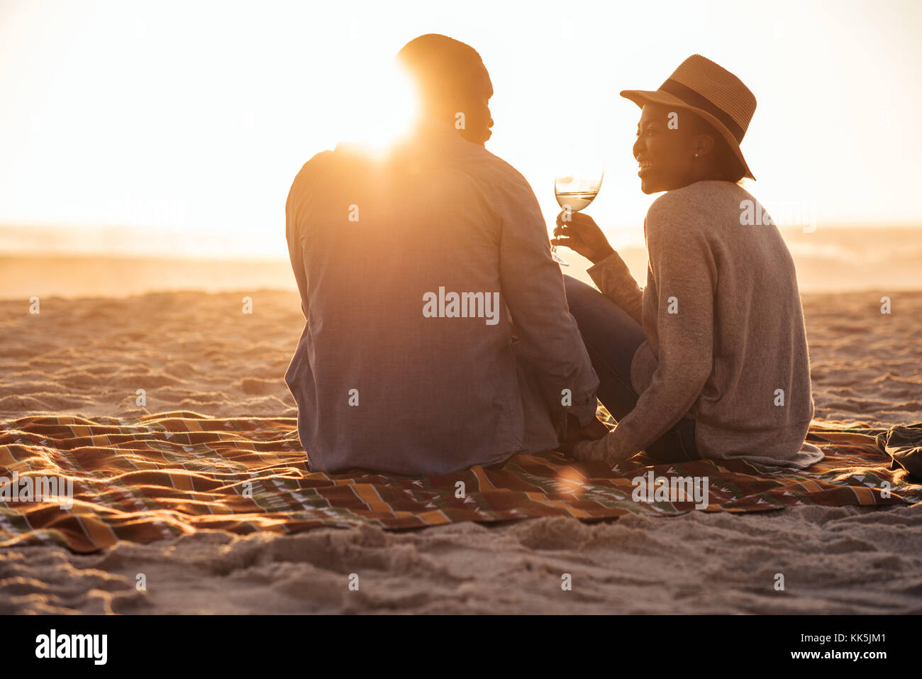 Junge afrikanische Paar beobachten ein Strand Sonnenuntergang und das Trinken von Wein Stockfoto