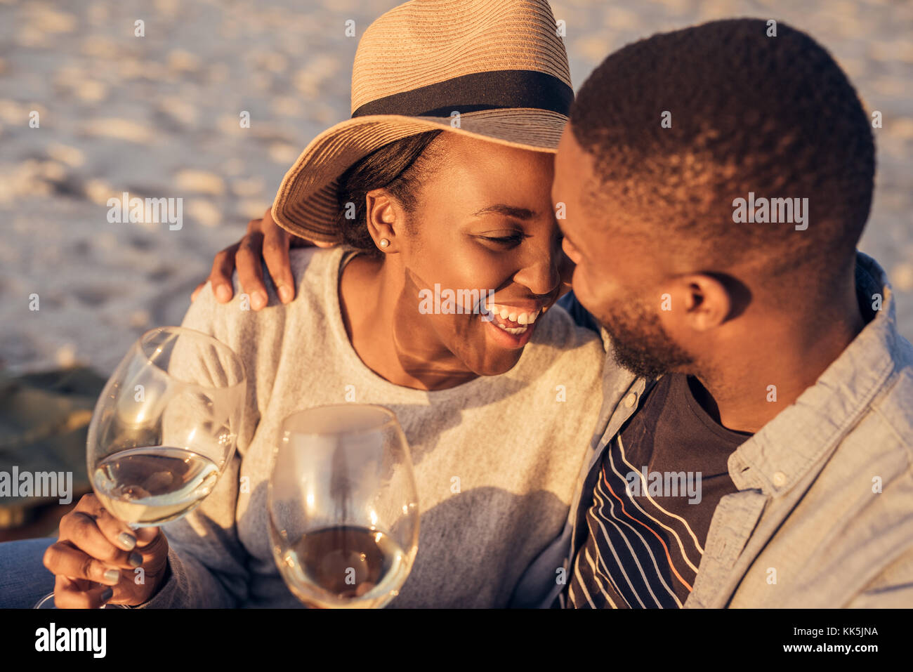Romantische junge afrikanische Paar Wein trinken gemeinsam am Strand Stockfoto