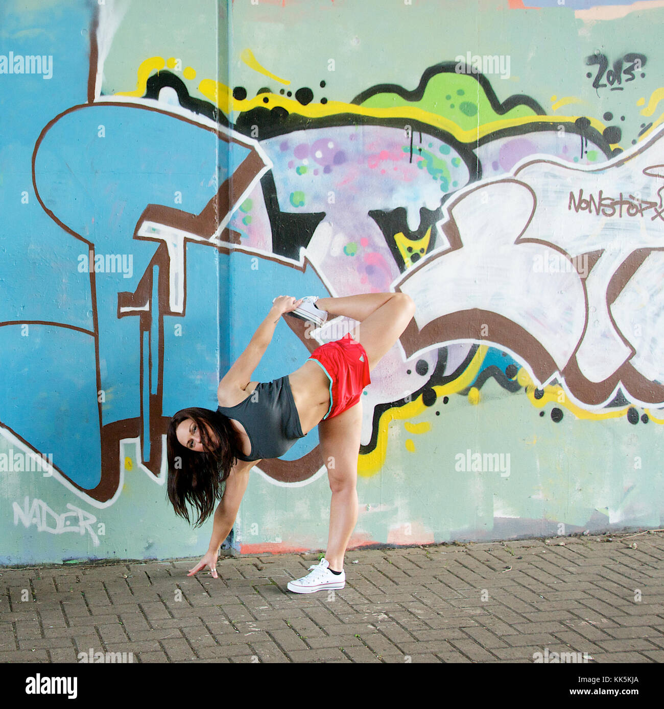 Mädchen Übungen in anoutdoor Lage mit Graffiti Hintergrund Stockfoto