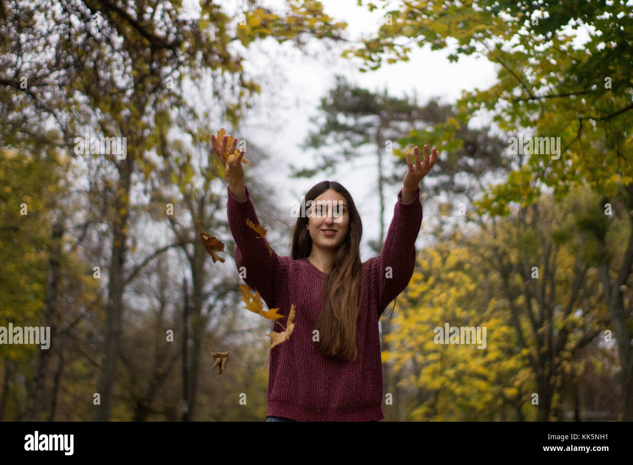 Mädchen in einem Park thowing Blätter, die sich im Herbst Landschaft gelb Blatt fallen nach ziemlich Stockfoto