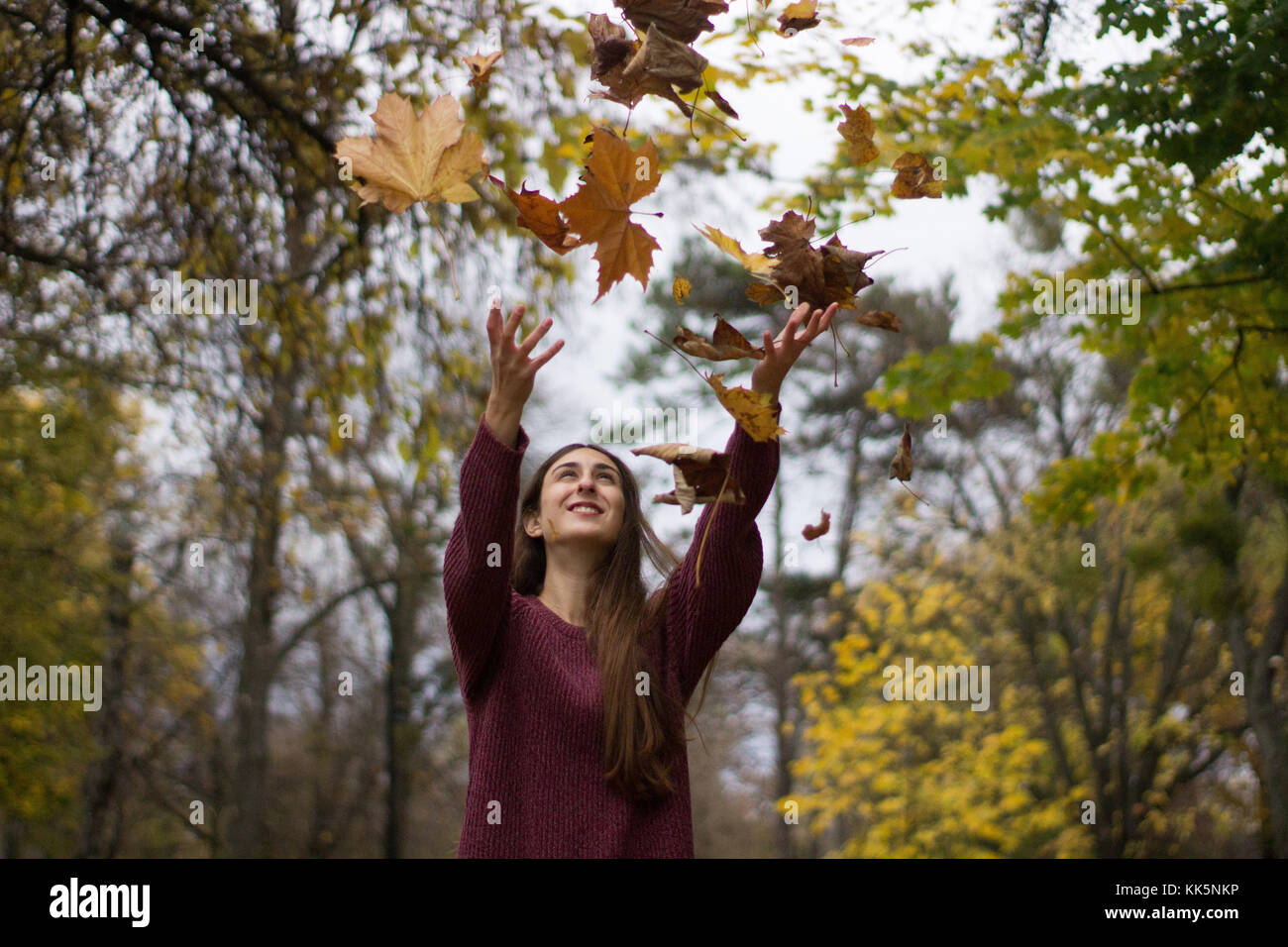 Mädchen in einem Park thowing Blätter, die sich im Herbst Landschaft gelb Blatt fallen nach ziemlich Stockfoto