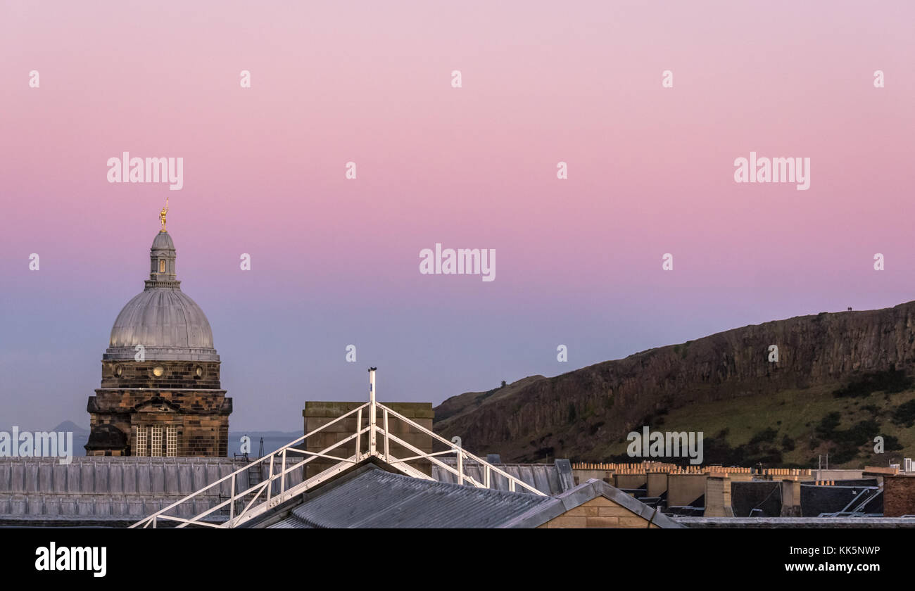 Blick auf die Skyline auf dem Dach, Die Old College Dome, die University of Edinburgh und die Salisbury Crags, Edinburgh, Schottland, Großbritannien, mit rosafarbenem Himmel bei Sonnenuntergang Stockfoto