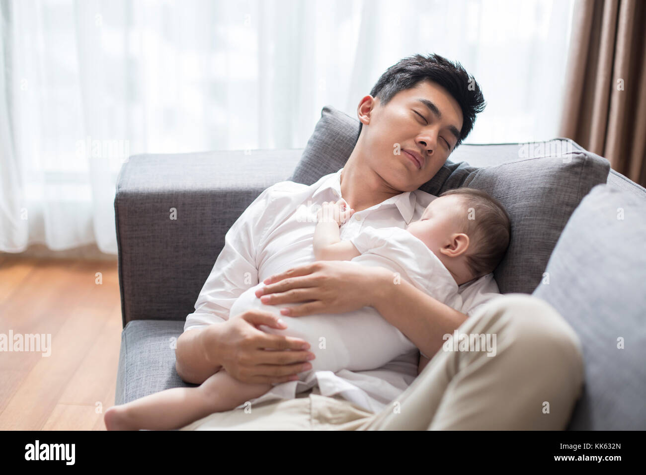 Junge chinesische Vater und Baby schlafend auf dem Sofa Stockfoto