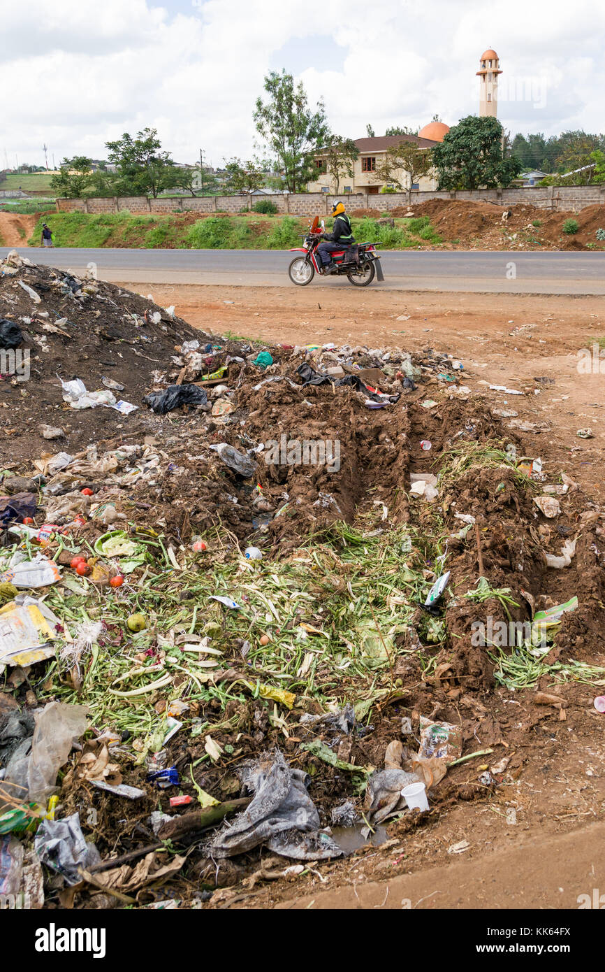 Ein Haufen Müll liegt auf der Straße wie ein Motorrad vorbeifährt, Kenia, Ostafrika Stockfoto