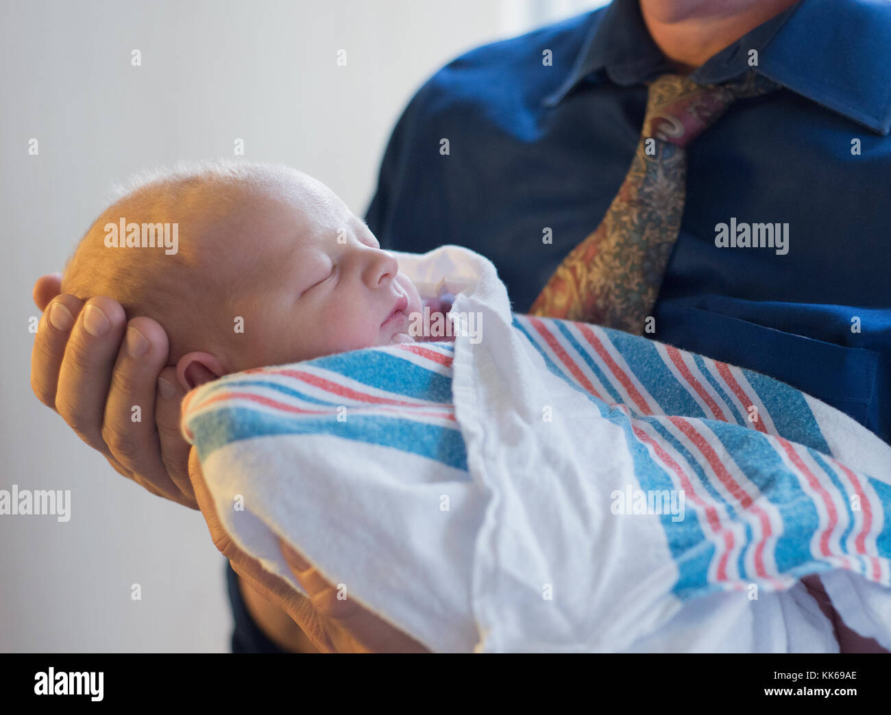 Ein Mann hält ein neugeborenes Baby. Stockfoto