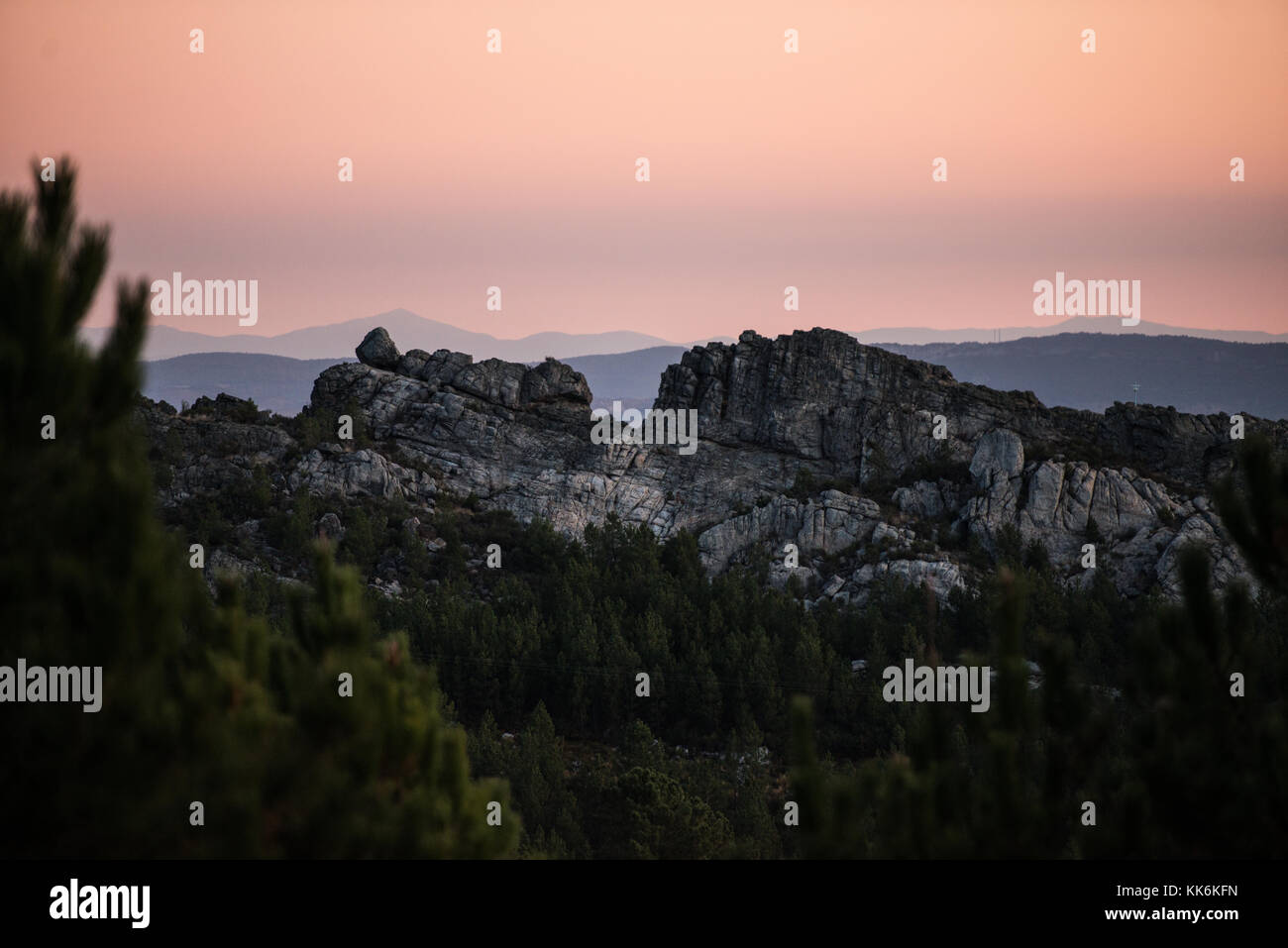 Blick zwischen den Ästen eines riesigen Pinienwald des steilen Profil von Puerto Roque von der Grenze zu Spanien und Portugal in der Morgendämmerung. Stockfoto