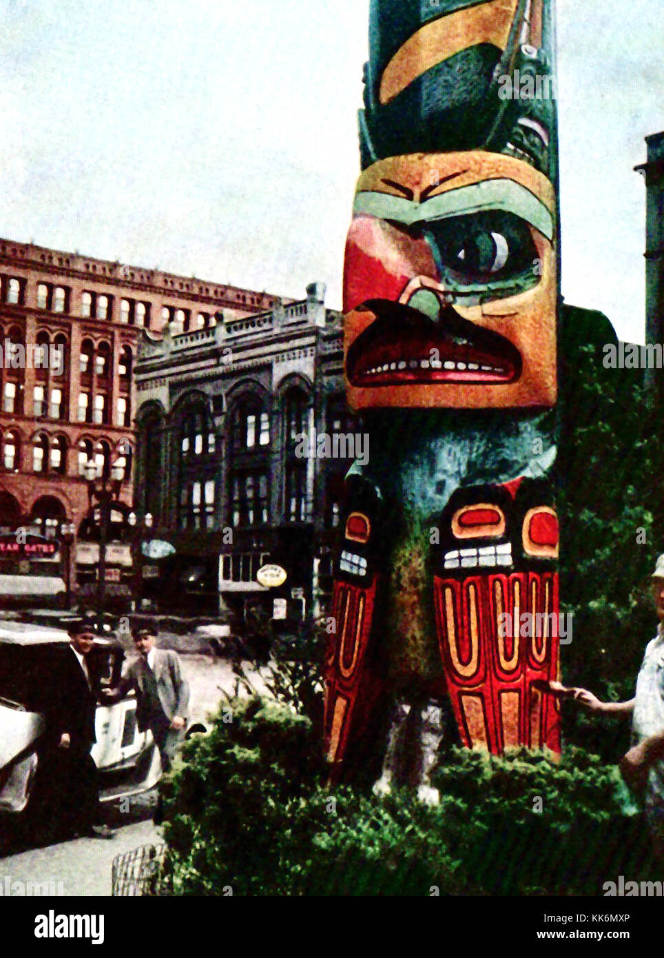 1933 - Vintage Farbfoto der gebürtigen indischen Totem Pole im Pioneer Square, Downtown Seattle. Ursprünglich aus der Tlingit Dorf Tongass. Auf der rechten Seite einen Mann gesehen, gibt es einen neuen Anstrich. Stockfoto