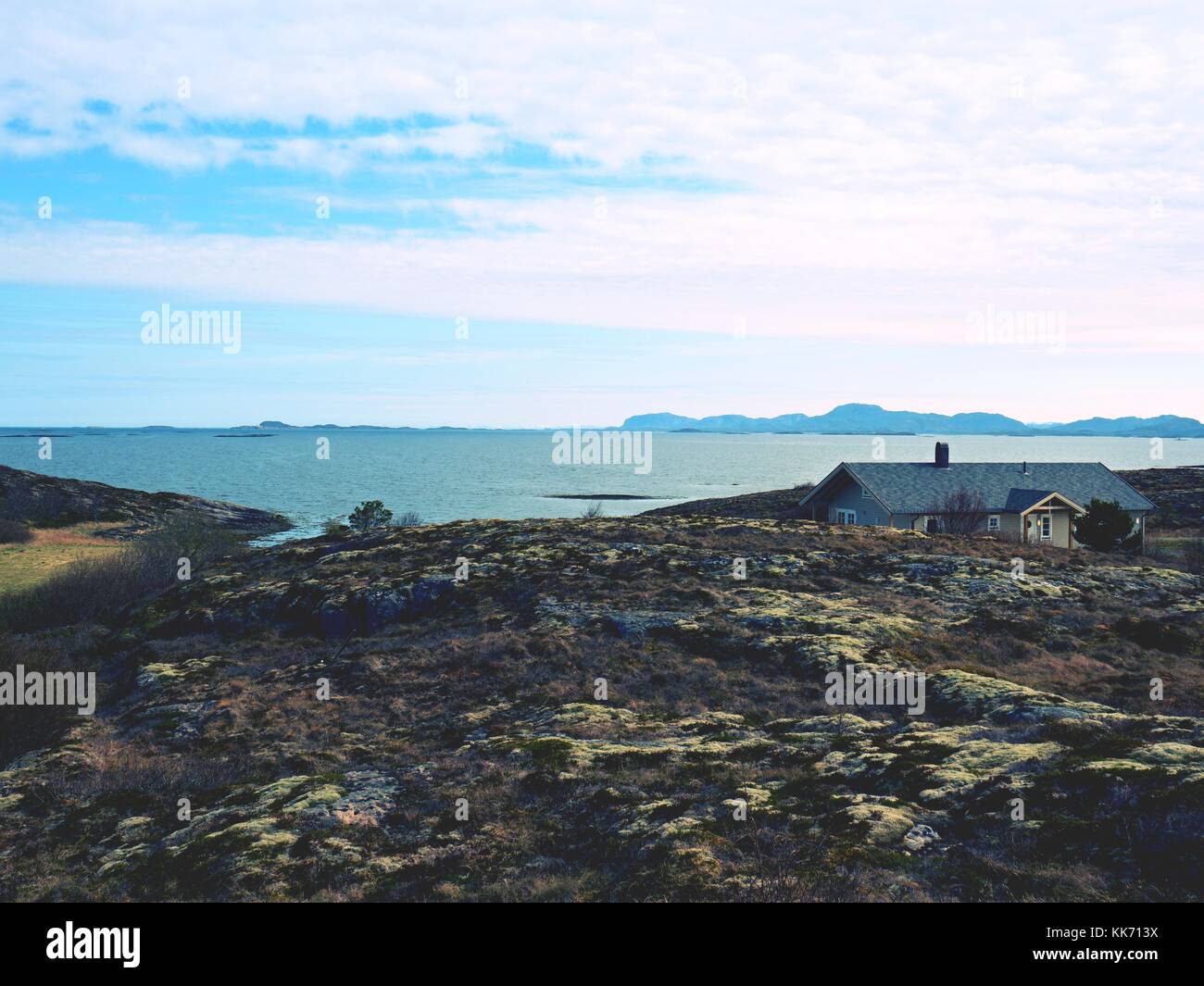 Moderne steinigen Familienhaus auf der Feder am Meer, Norwegen Insel. Ein traditionelles Steinhaus mit einem wunderschönen Blick auf das Meer Bucht. felsige Landschaft mit Stockfoto