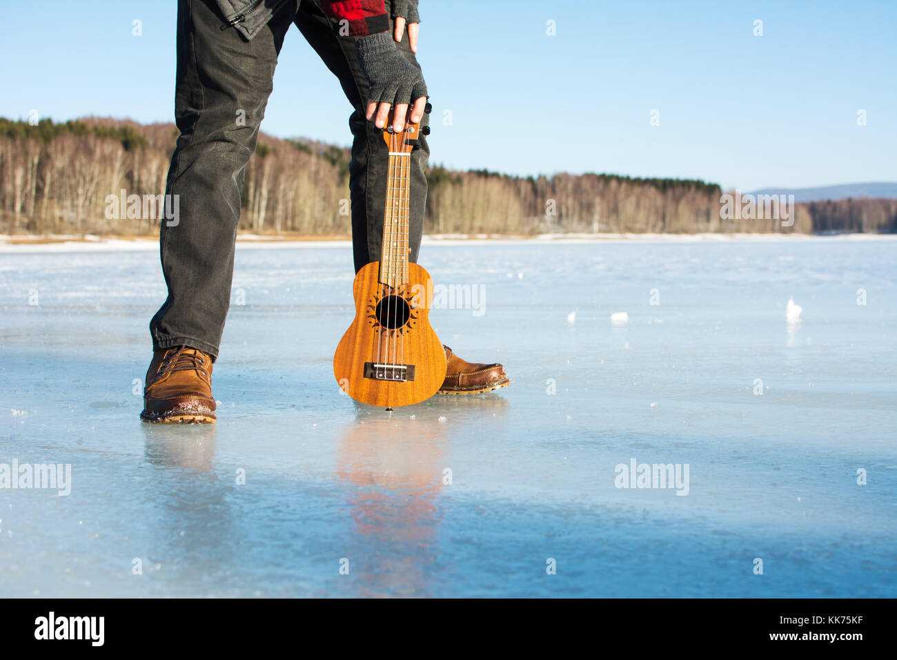 Mann mit ukelele stehend auf einem zugefrorenen See Stockfoto