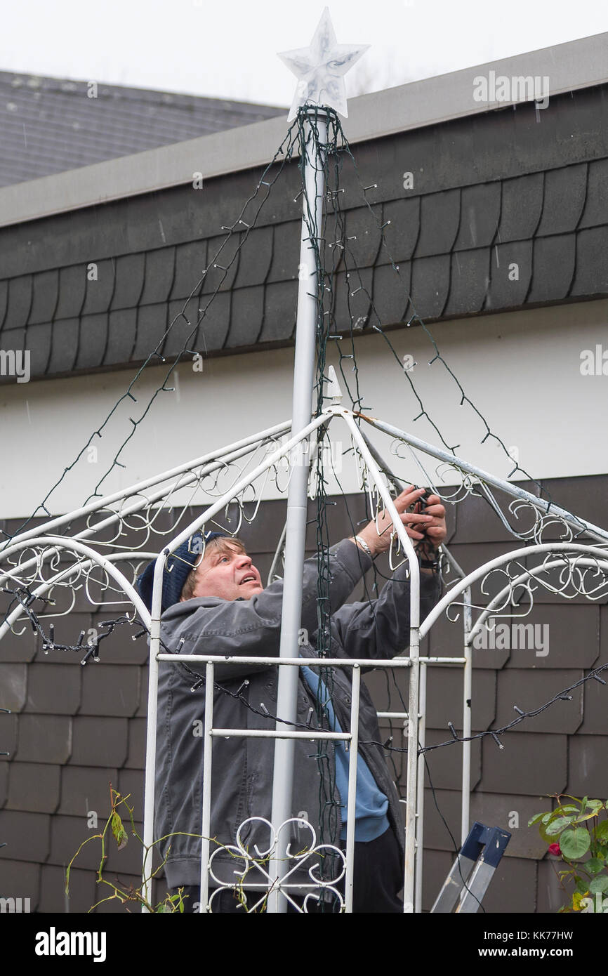 Man schmückt den Garten mit Lichterkette während es regnet Stockfoto