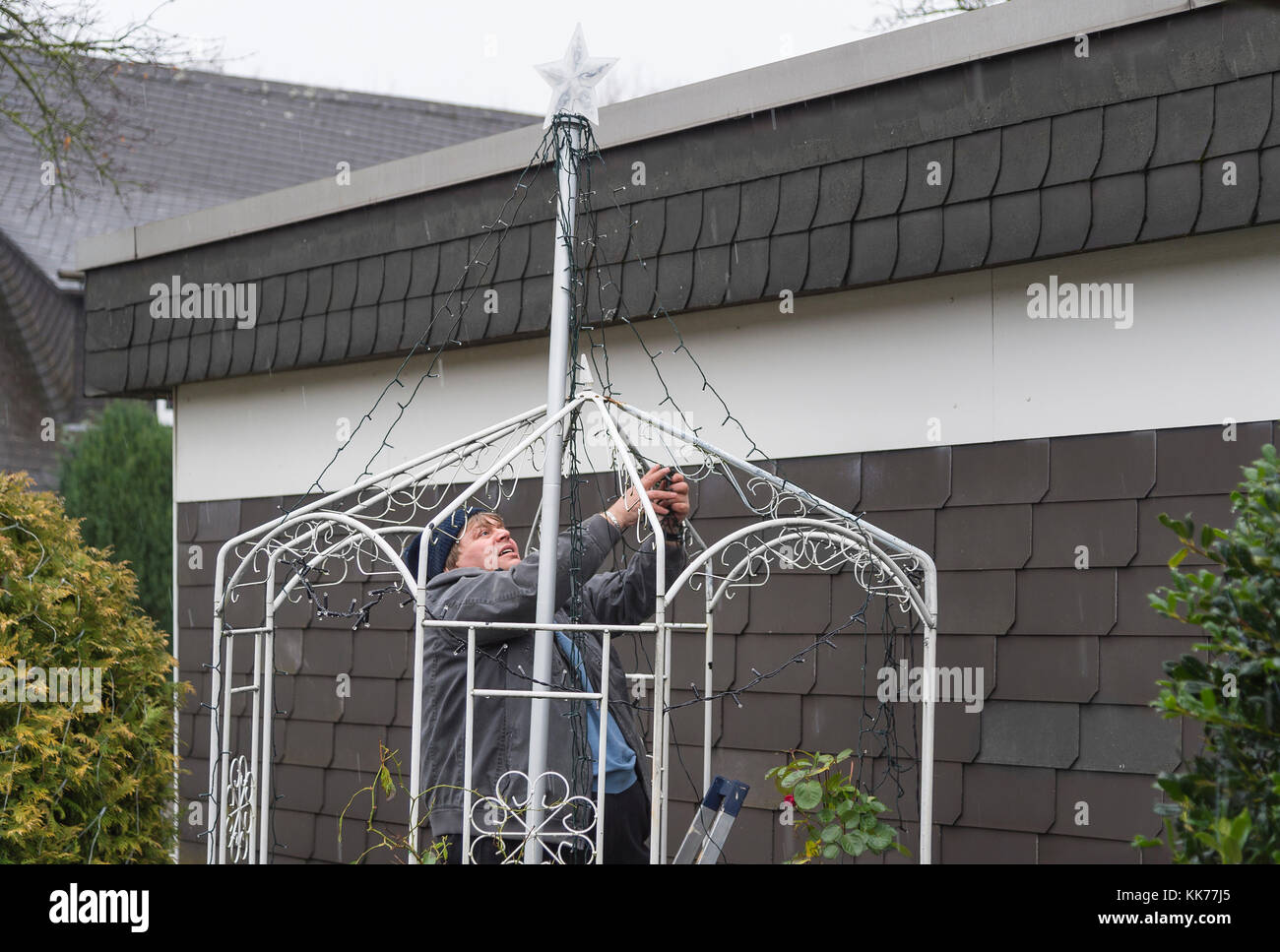 Man schmückt den Garten mit Lichterkette während es regnet Stockfoto