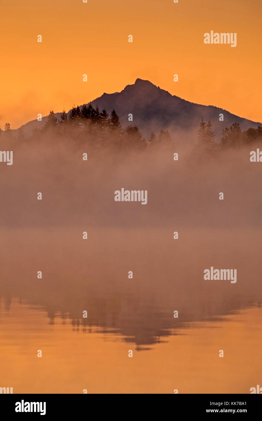 Mount Pichuck Sonnenaufgang mit Nebel und Bäume entlang weit Shoreline mit Reflexionen Stockfoto