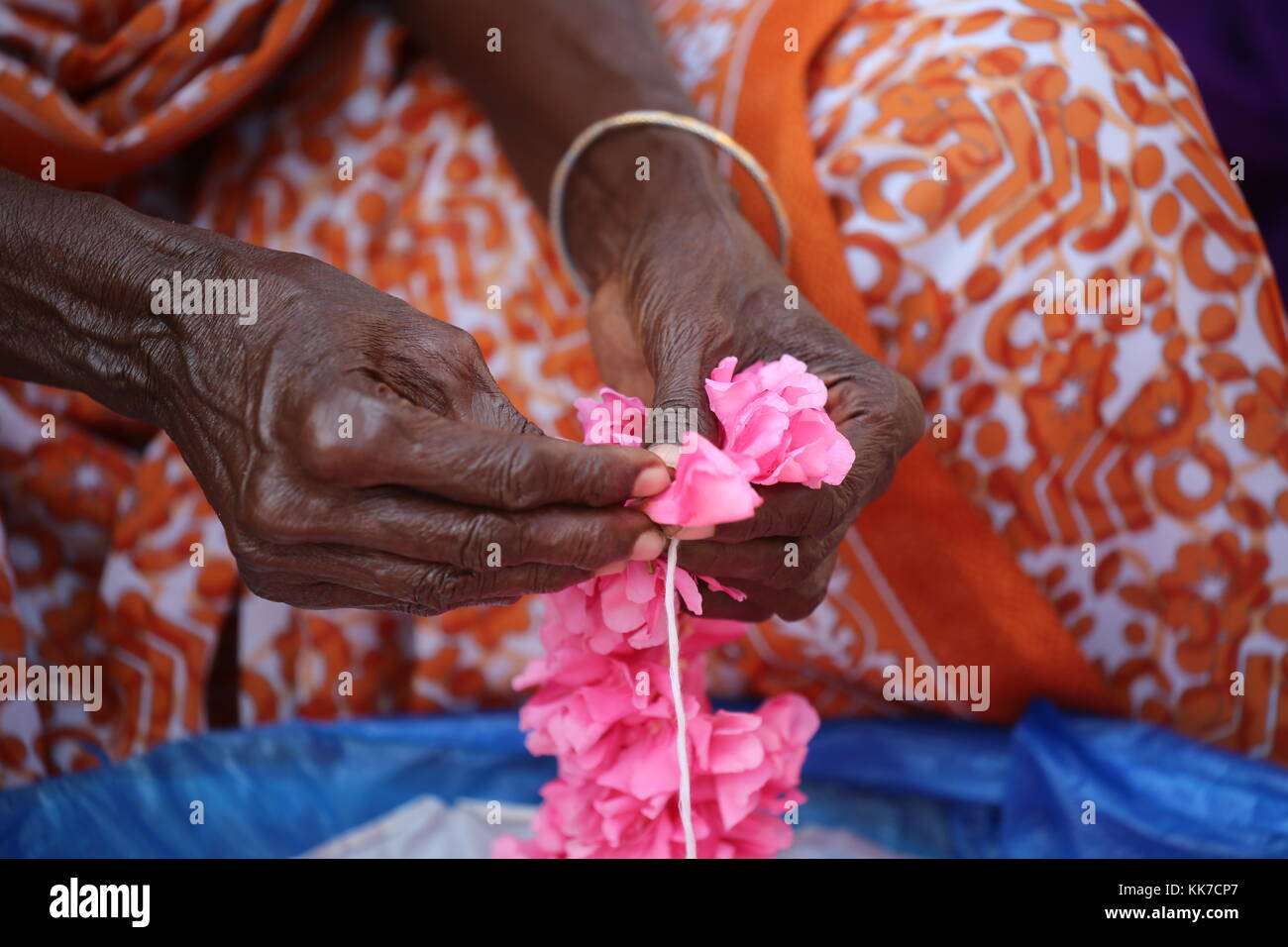 Indische Frau flechten mit Schnur Blumen zu einer Girlande für den Tempel - indische Frau Geflecht mit string Blumen auf eine Girlande für den Tempel Stockfoto