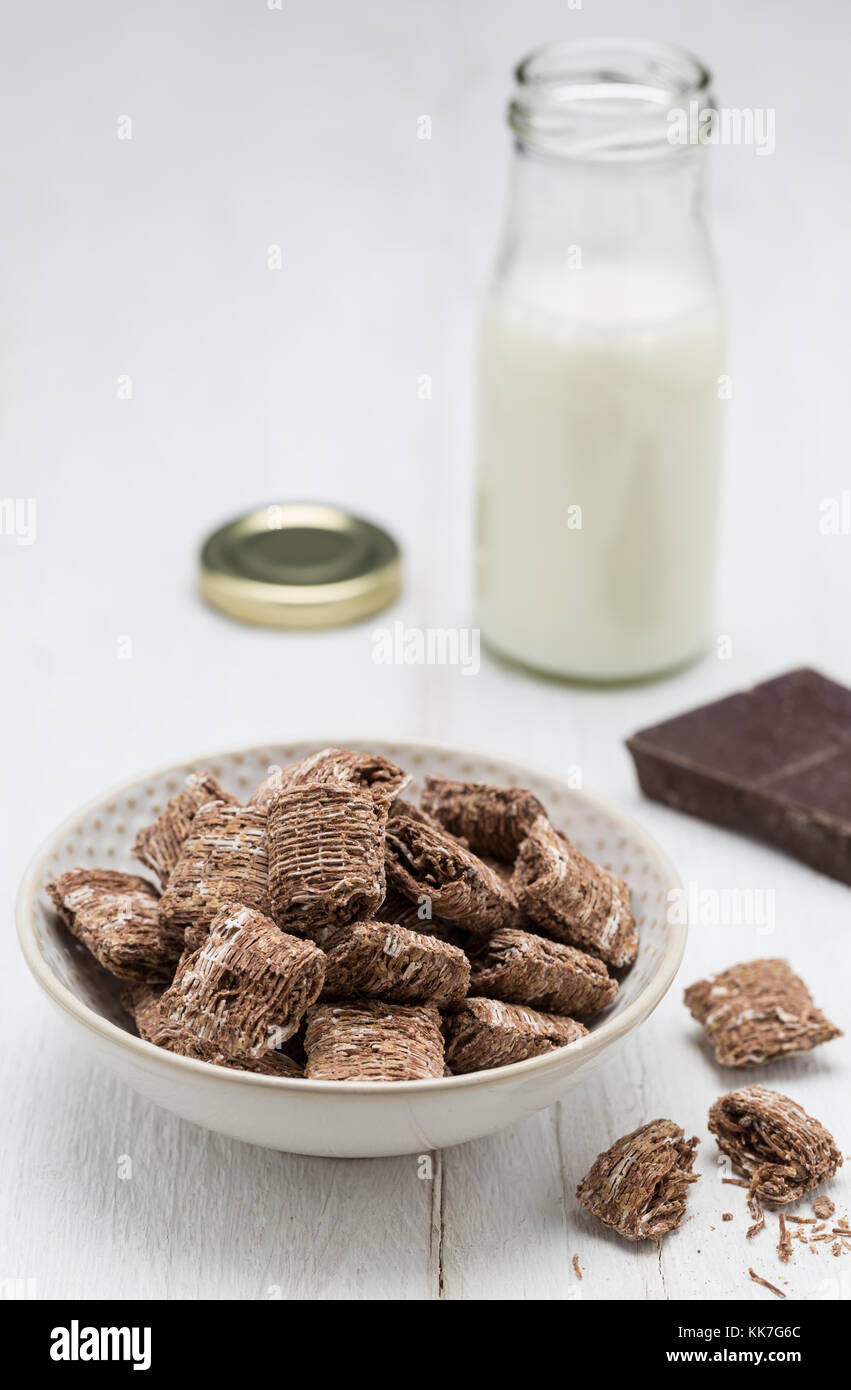 Schokolade Weizenflocken in eine Schüssel geben und die Milch aus der Flasche. Stockfoto