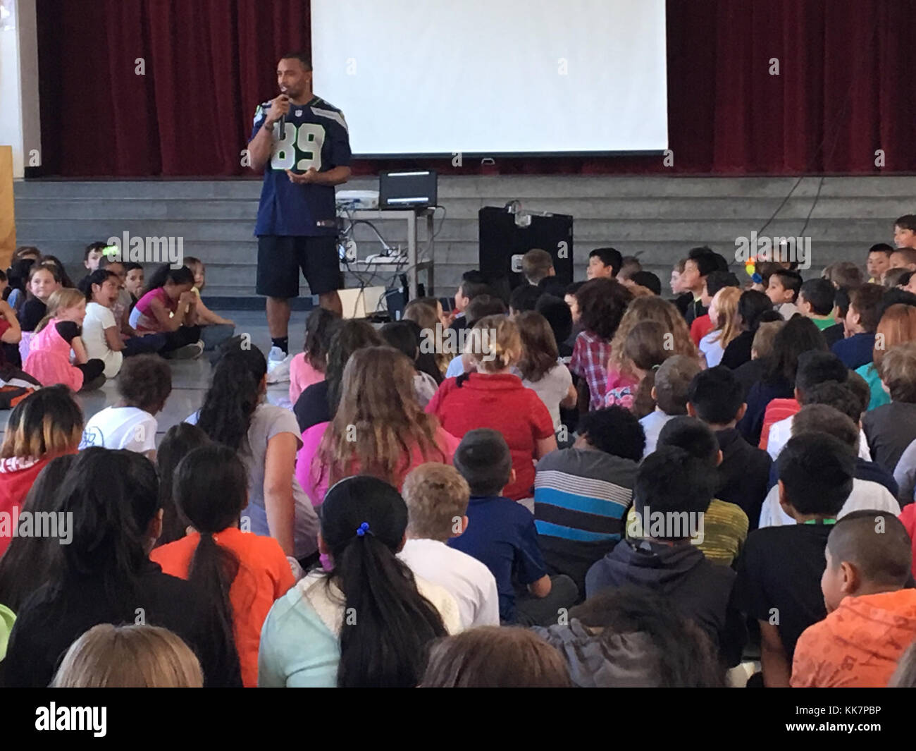 Seahawk-Star Doug Baldwin erzählt Kindern von der Tillicum Elementary School in Lakewood, dass sie bei einer Überraschungsversammlung in der Nähe von Bahngleisen sicher sein müssen. Bleiben Sie zurück von den Gleisen 34304365261 o Stockfoto