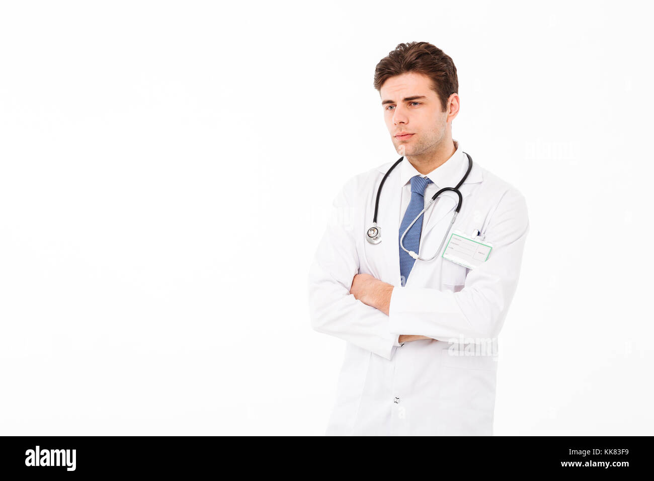 Porträt eines nachdenklichen jungen männlichen Arzt mit Stethoskop in Uniform stehend mit dem Arm auf dem Kinn gekleidet und Wegsehen bei copy Raum über isoliert Stockfoto