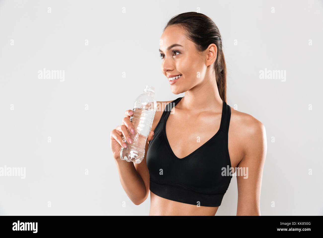 Bild der glückliche junge Sport Frau posiert auf grauen Hintergrund isoliert. Neben der Suche Trinkwasser. Stockfoto