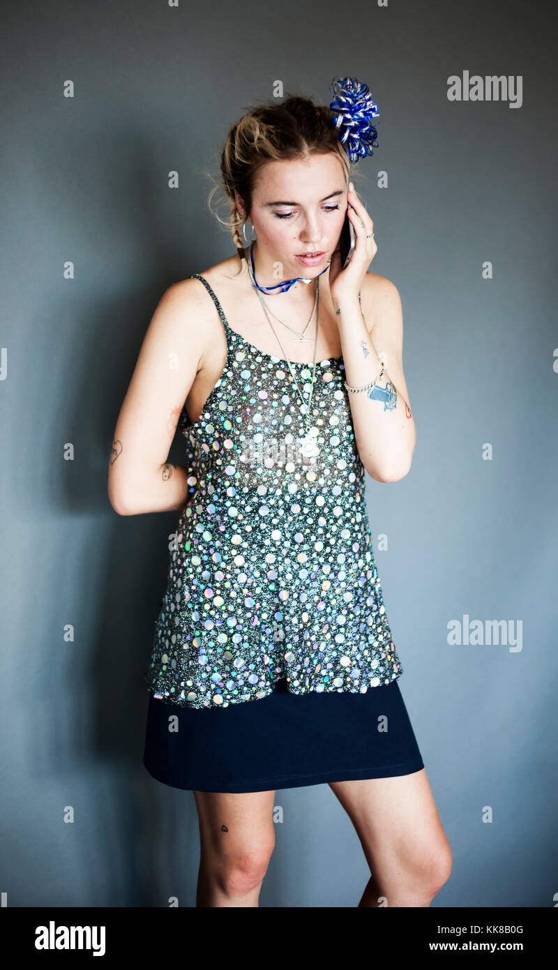 Junge hübsche Frau mit holographischen sparkly Top und Minirock auf Handy sprechen, Modell Release verfügbar, London, 18/06/2017 Stockfoto