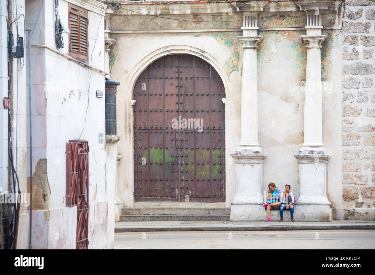 Zwei jungen kubanischen Frauen warten außerhalb einer alten Kirche in Havanna, Kuba Stockfoto