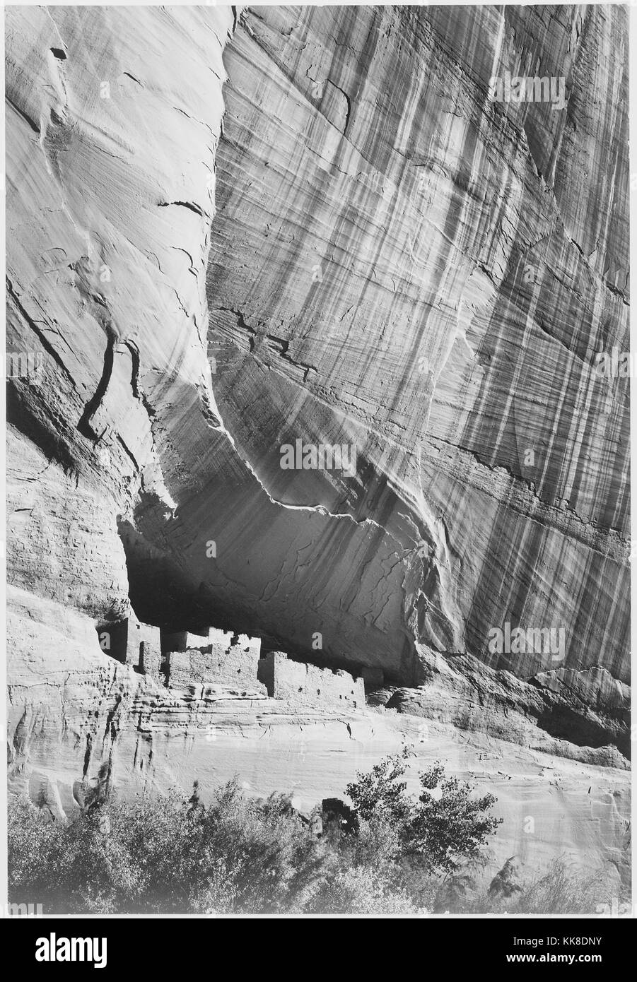 Ein schwarz-weiß Foto einer Siedlung am Fuße einer Klippe in Canyon de Chelly National Monument geschaffen, die Gegend ist eine der ältesten ununterbrochen bewohnten Gebiete in Nordamerika, es wird von den Navajo Tribal Vertrauen der Navajo Nation und wird in Zusammenarbeit mit dem National Park Service verwaltet, das Bild stammt aus einer Serie von Fotografien bekannt als das Wandbild Projekt von Ansel Adams, er durch den National Park Service 1941 beauftragt wurde, eine fotografische Wandbild für das Ministerium des Innern in Washington DC zu erstellen, wird das Projekt zu einem Ende kam wegen des Zweiten Weltkrieges, Stockfoto
