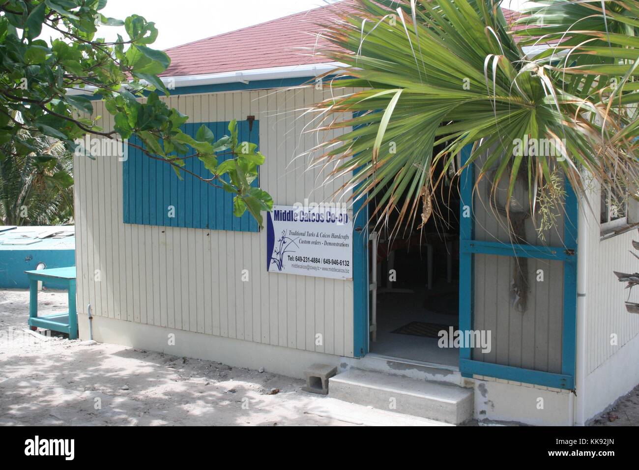Ein Foto von der Außenseite des Mittleren Caicos Co-Op, die hölzernen Gebäude auf die Fenster und Türen lackiert ist weiß und Akzente in Blau, Palmen im Vordergrund und Hintergrund gesehen werden kann, der Speicher stellt lokale Künstler, Souvenirs für Touristen produzieren, Turks- und Caicosinseln, 2013. Stockfoto