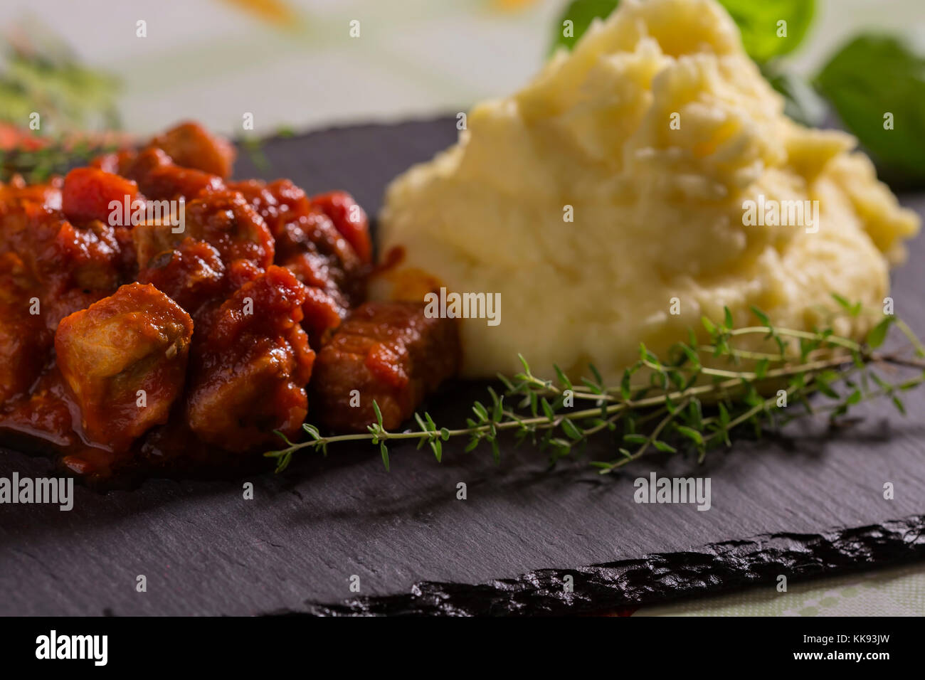 Schweinefleisch Eintopf in Tomatensauce mit Kartoffelpüree und Kräuter Stockfoto