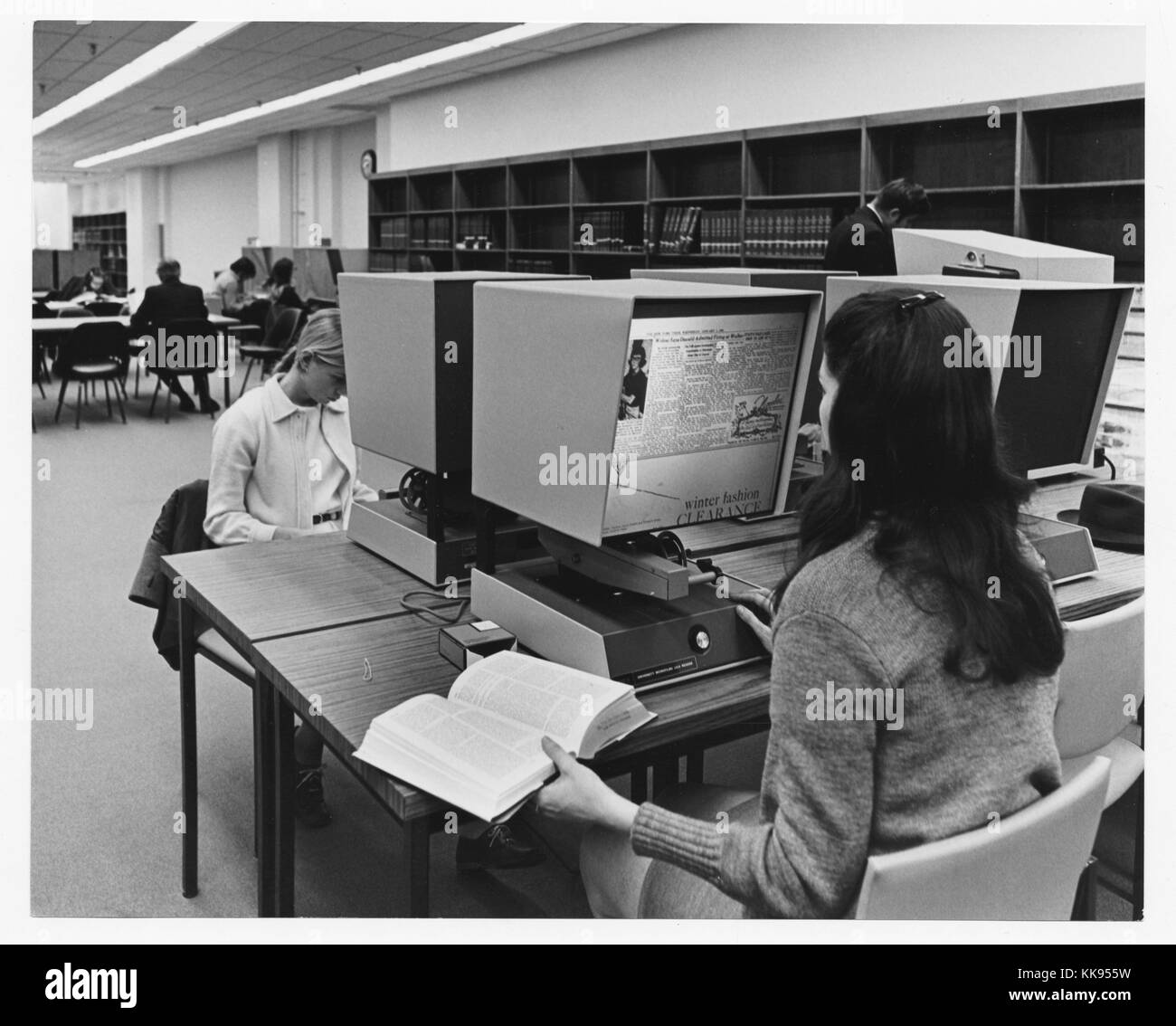 Schwarz-weiß Foto von zwei Frauen, die einander gegenüber sitzen, mit mikrofilm Zuschauer, in einer Bibliothek, New York City, New York, 1970. Von der New York Public Library. Stockfoto