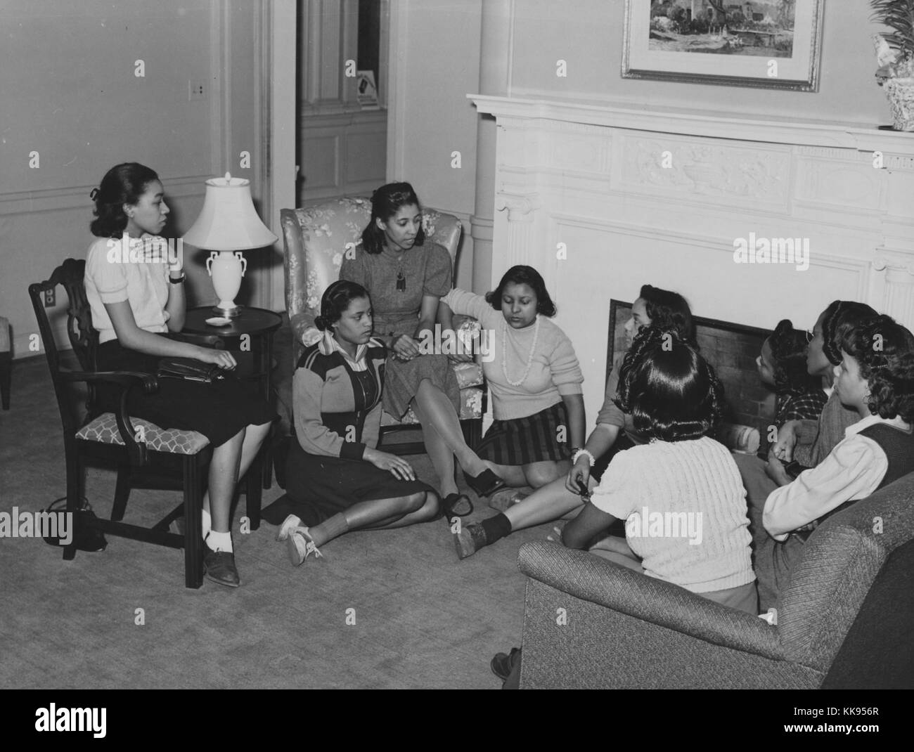 Ein Foto der jungen Frauen treffen mit einem Ausbilder vom National Youth Administration, sind sie zusammen in einem Wohnzimmer versammelt, einige der jungen Frauen auf dem Boden sitzen, da es nicht genügend Sitzplätze für alle, die NYA war eine Organisation als Teil von Franklin Roosevelts New Deal, das Ziel der Agentur gebildet wurde, um Ausbildungs- und Arbeitsplätze für Amerikaner zwischen 16 und 25 Jahren, von 1935 bis 1939 betrieben, dieses Treffen in der Gute Hirte Community Center in Chicago, Illinois, 1877 stattfand. Von der New York Public Library. Stockfoto