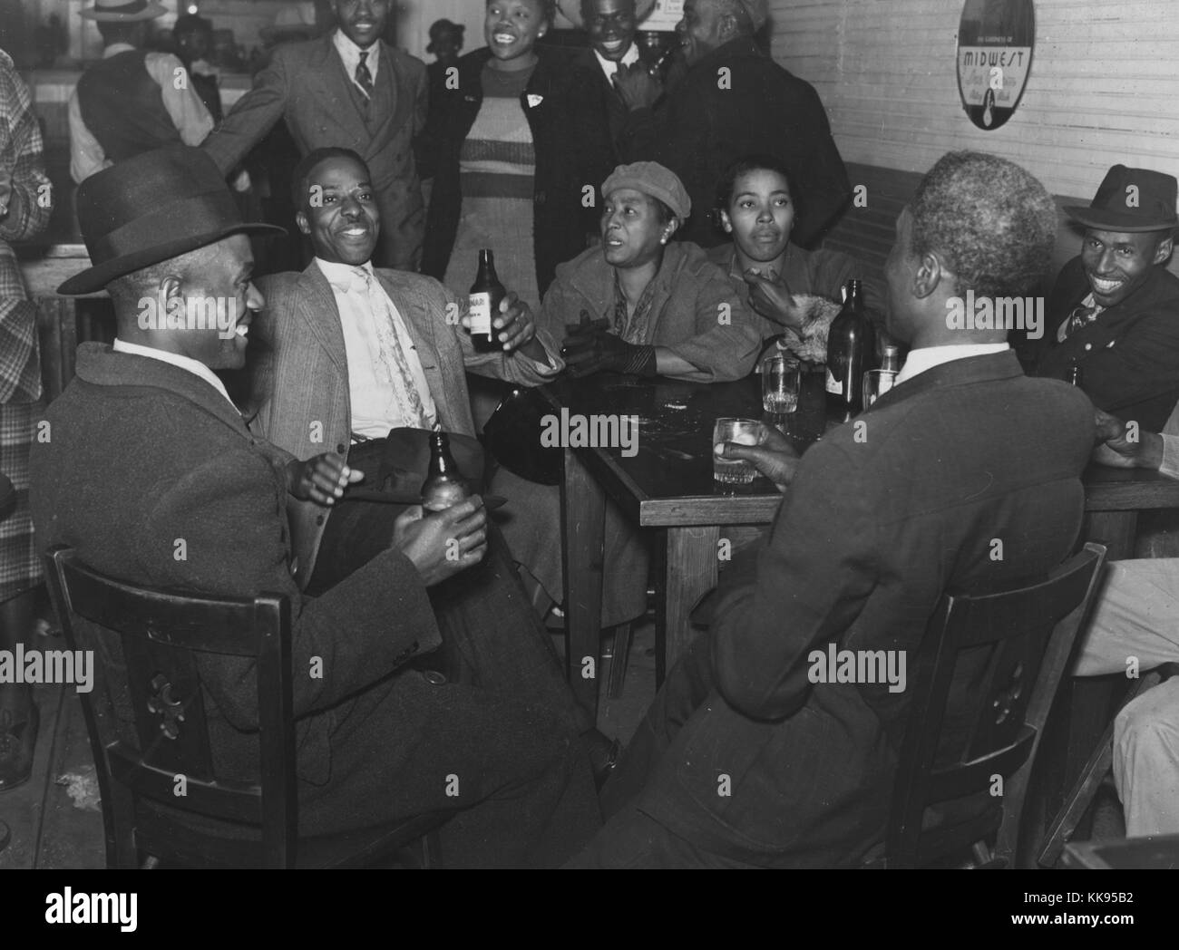 Schwarz-weiß Foto der afroamerikanischen Männern und Frauen in Anzügen und Kleidern, Sitzen und Stehen, trinken an der Bar, Clarksdale, Mississippi Delta, Mississippi, 1939. Von der New York Public Library. Stockfoto