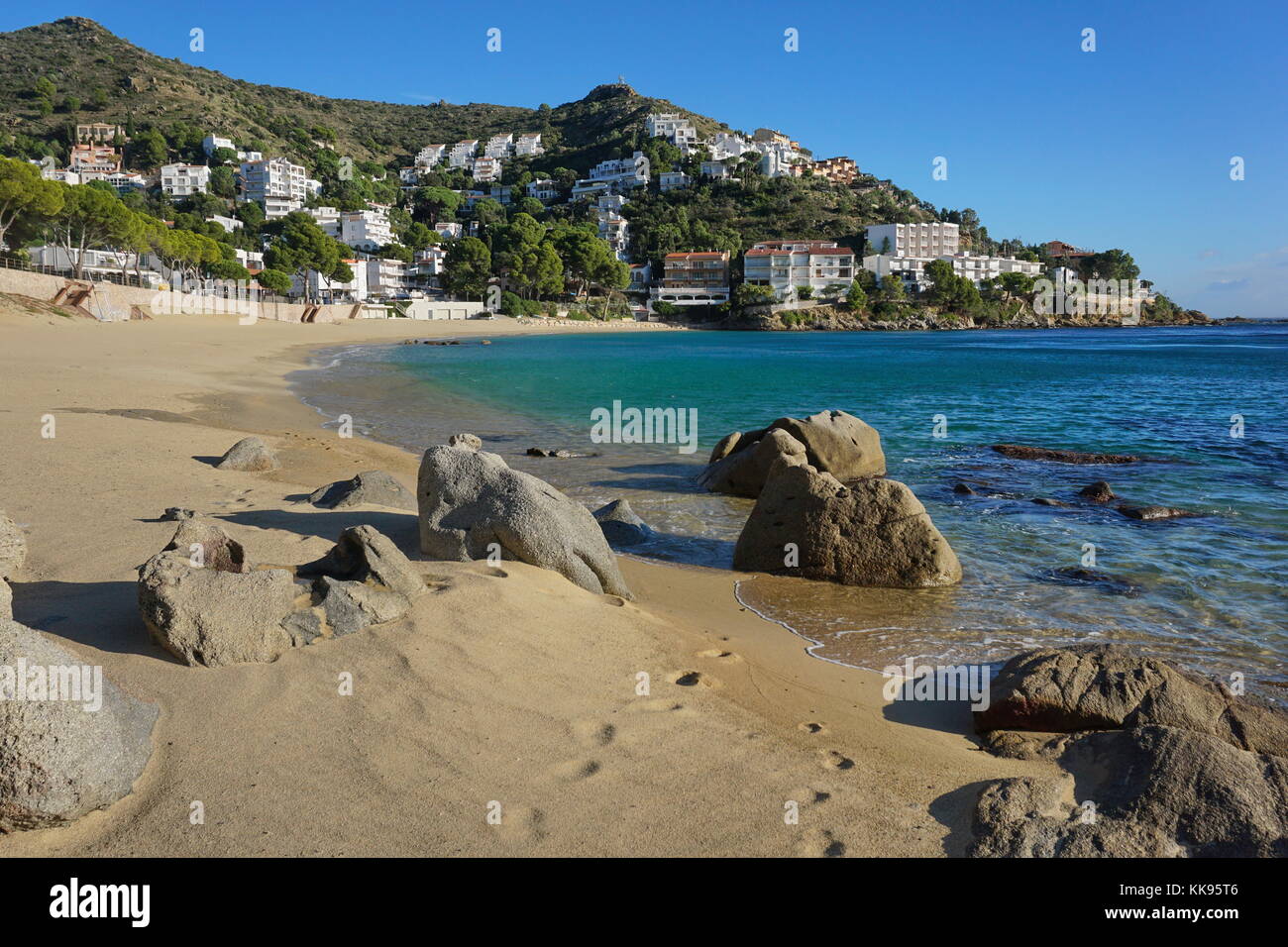 Spanien Costa Brava, Sand und Felsen an der Küste mit dem Gebäude im Hintergrund, Canyelles Petites Strand, Roses, Girona, Katalonien, Mittelmeer Stockfoto