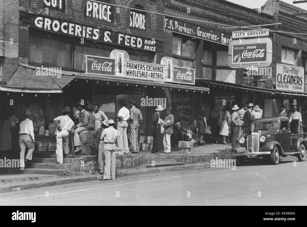 Schwarz-weiß Foto von einer Versammlung von Menschen, an einem Samstag Nachmittag, vor der Stadt unternehmen, Zeichen für ein Lebensmittelgeschäft und Reiniger können gesehen werden, San Agustino, Texas, 1939. Von der New York Public Library. Stockfoto