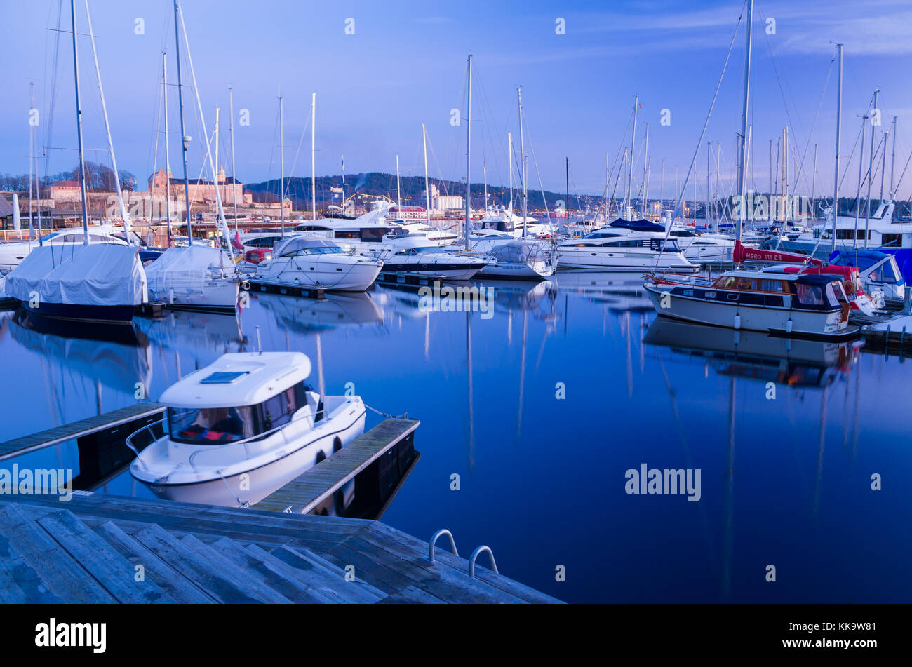 Winterschlaf in Aker Brygge marina, Oslo, Norwegen. verschlossen Yachten festmachen zu floating Piers, mit Akershus Festung im Hintergrund. Stockfoto