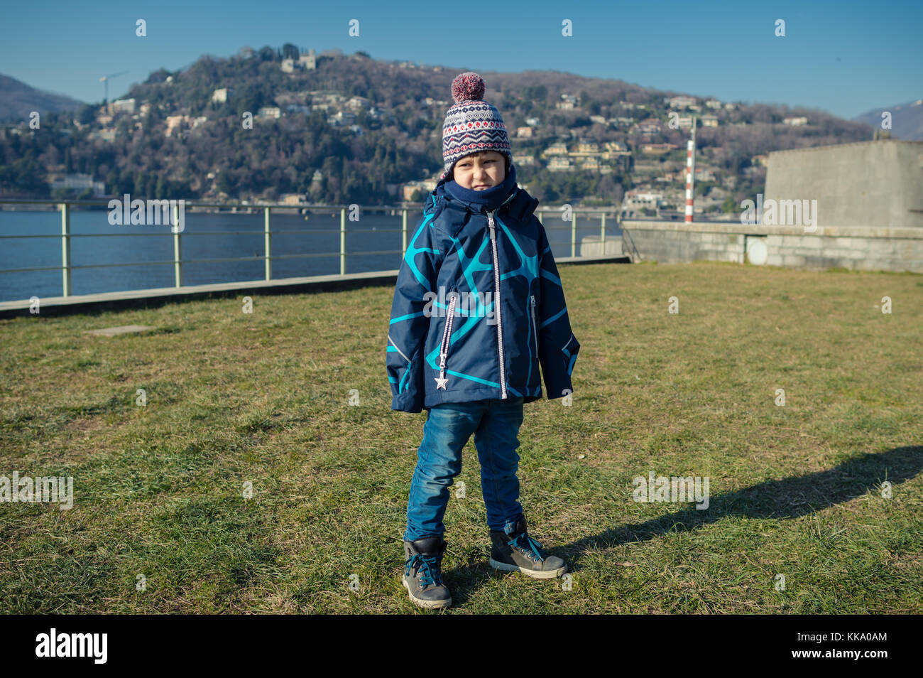 Junge stehend auf dem Gras in der Nähe des Sees und der Macht Gesichter Stockfoto