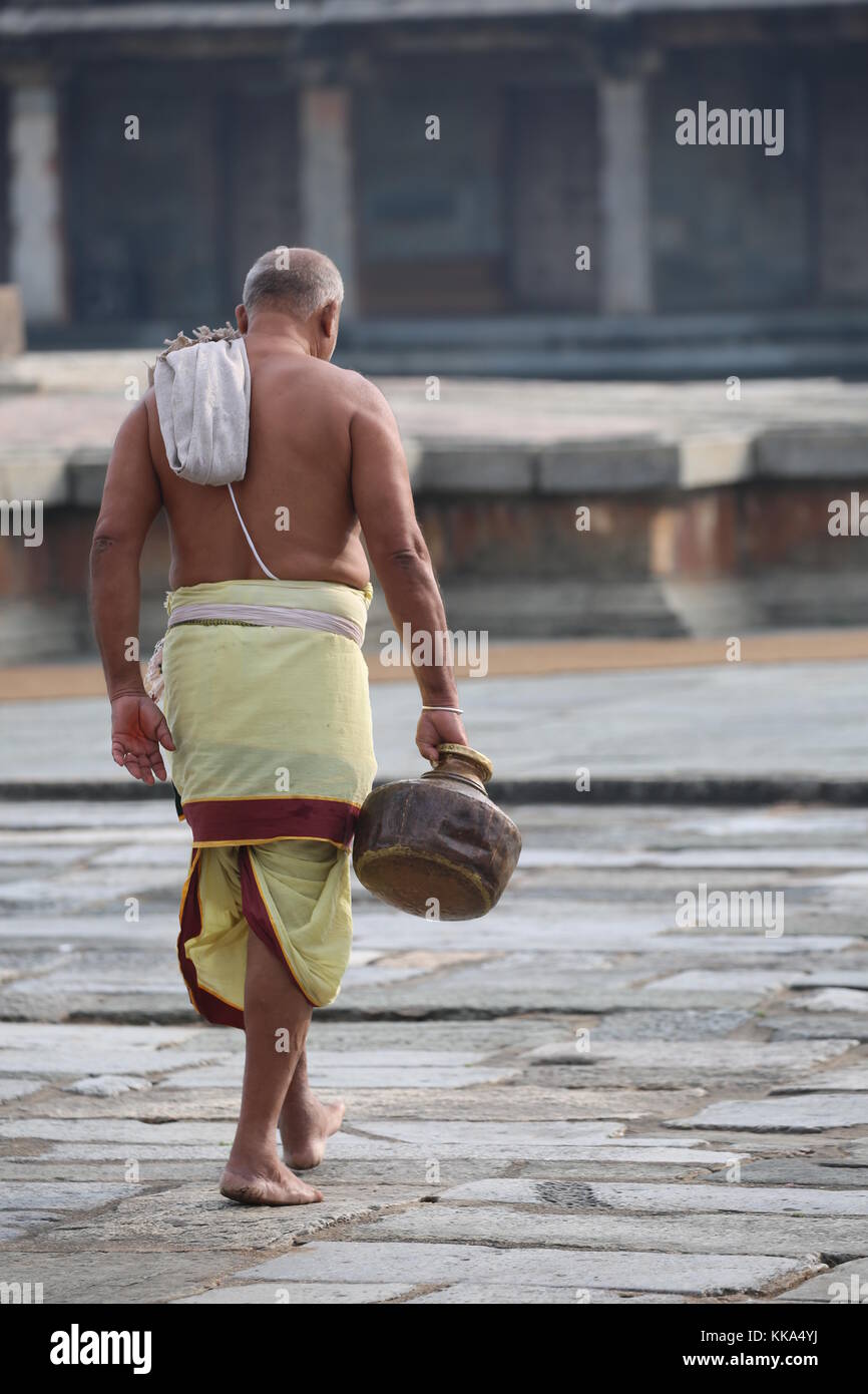 Morgen im Chenna Keshava Vishnu Tempel - Priester mit lota kalash Topf Opfergaben - Priester mit Kuferkrug beim Wasser holen Stockfoto