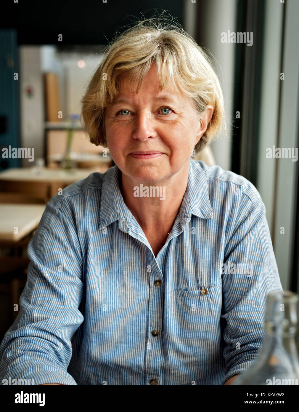 Lächelnde blonde Frau in einem Restaurant. Alter 55-65 Stockfoto