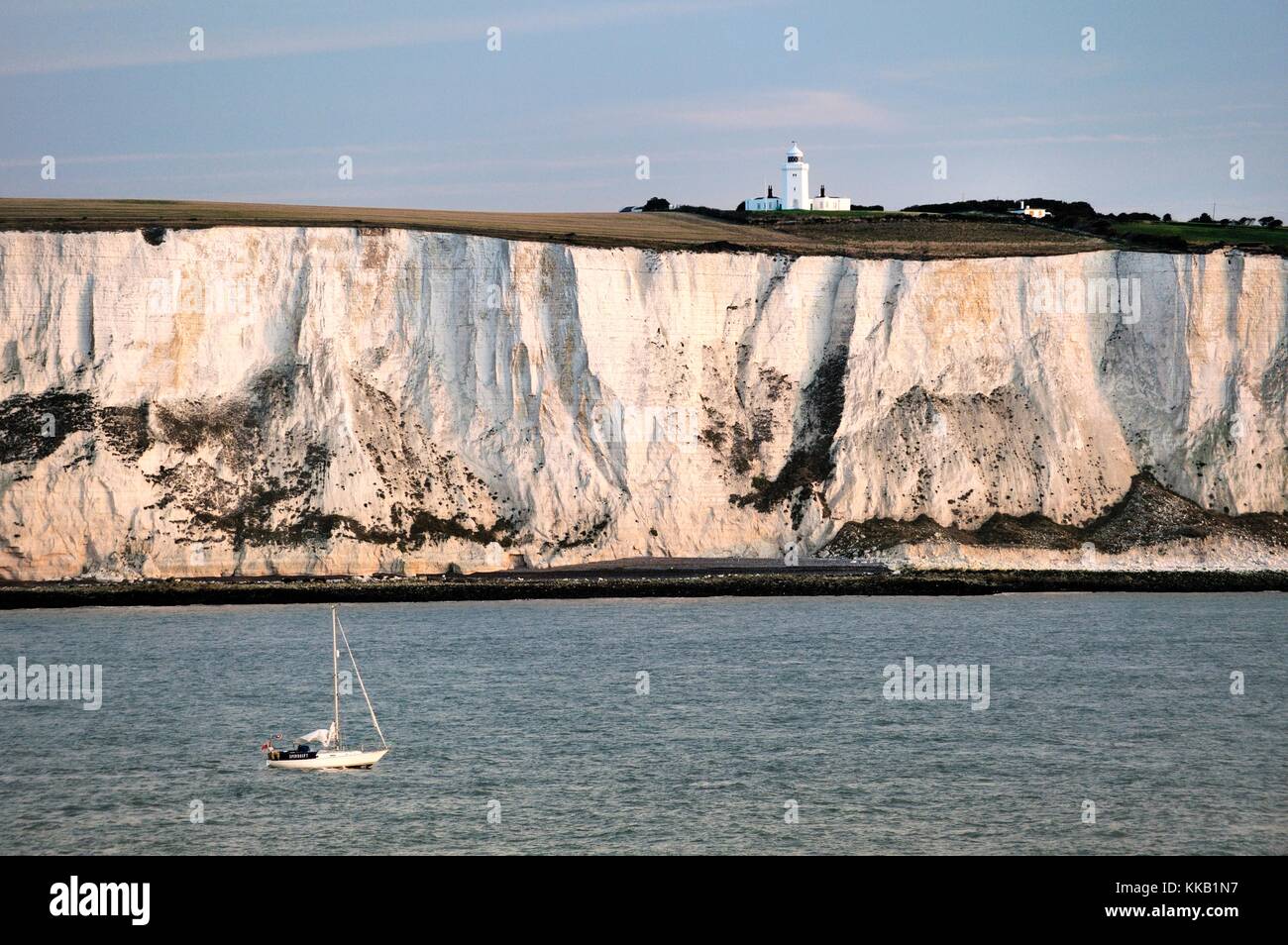Yacht vorbei an den Weißen Felsen von Dover in der englischen Kanal östlich von Dover unten Süden Forland Leuchtturm. Dawn Licht Stockfoto