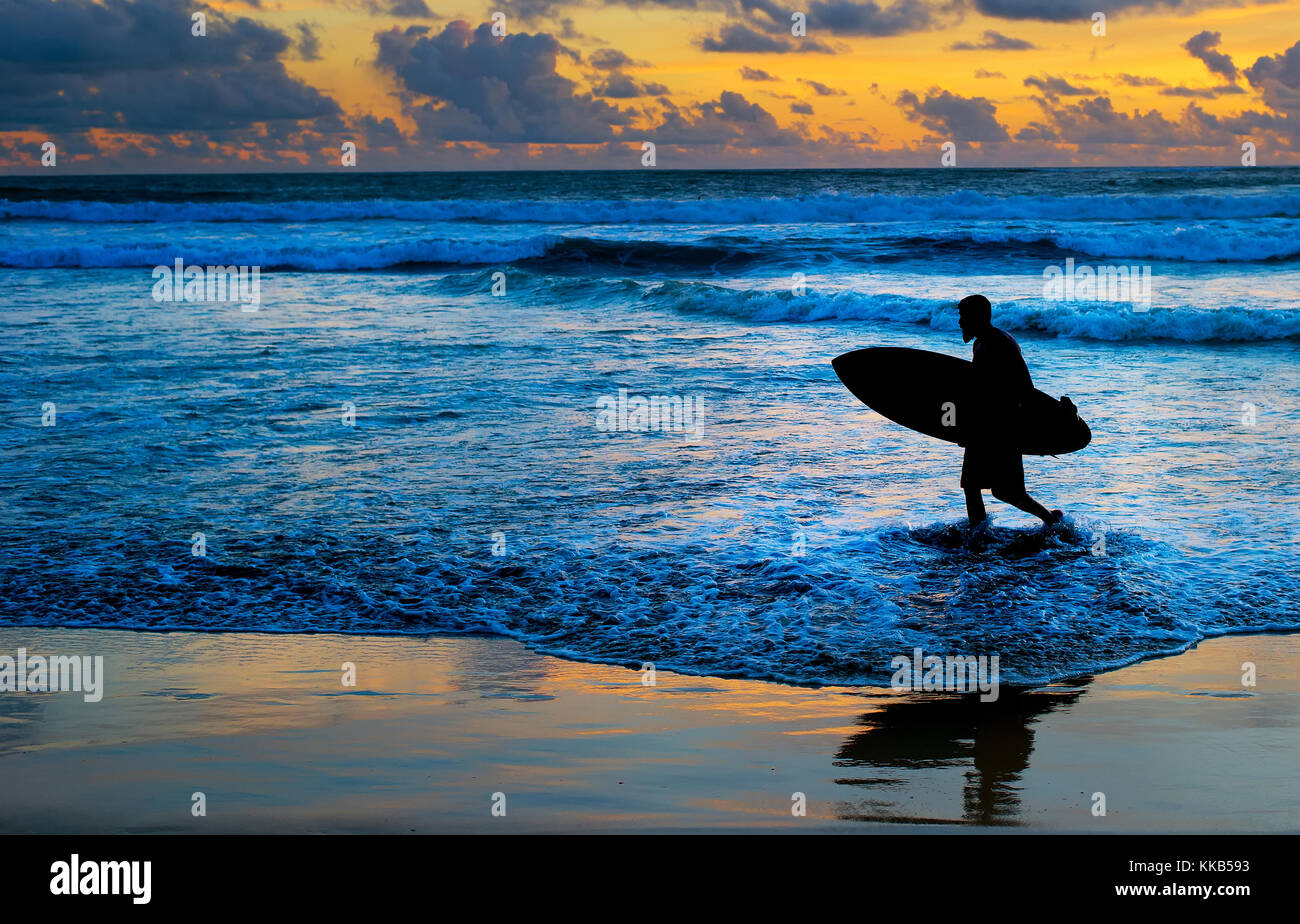 Surfer am Strand mit Surfbrett bei Sonnenuntergang. Insel Bali Stockfoto