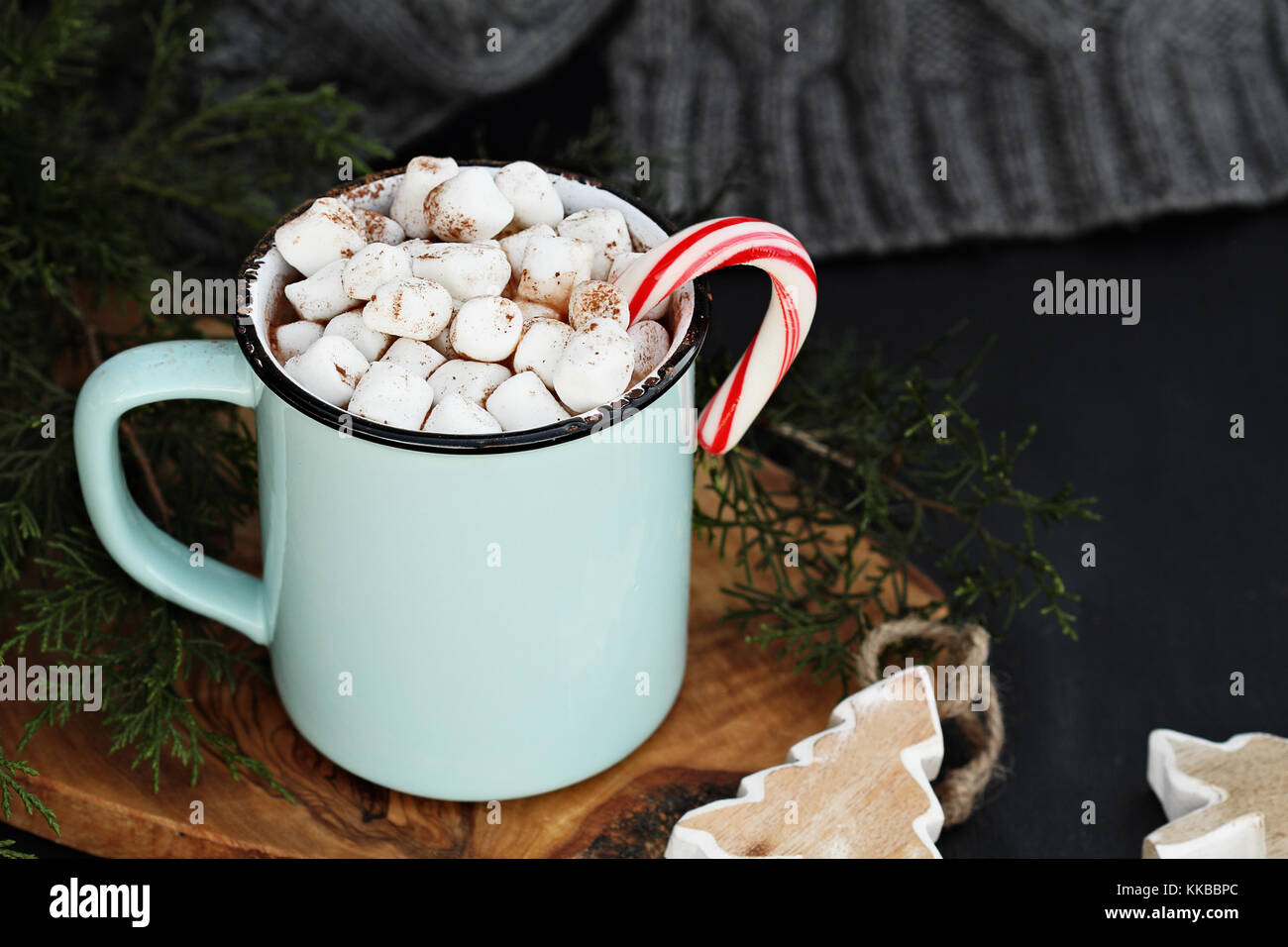 Emaille Tasse heißen Kakao trinken mit Marshmallows und Candy Cane gegen eine rustikale Hintergrund mit schönen Holz Christbaumschmuck und eine graue sca Stockfoto