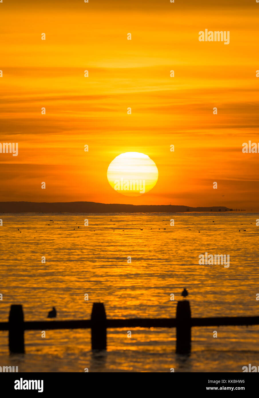 Sonnenuntergang über dem Meer knapp über dem Horizont, auf der britischen Südküste. Stockfoto