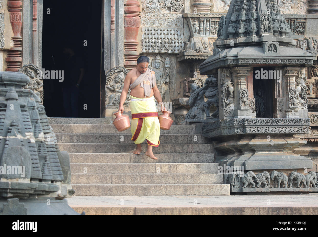 Morgen im Chenna Keshava Vishnu Tempel - Priester mit lota kalash Topf Opfergaben - Priester mit Kuferkrug beim Wasser holen Stockfoto