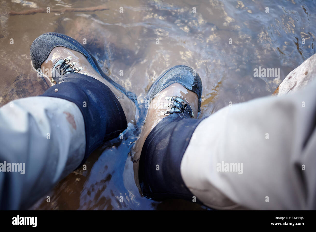 Mann, Wanderschuhe in einen Bach mit seinen Füßen untergetaucht im Wasser in eine First Person Sicht Stockfoto