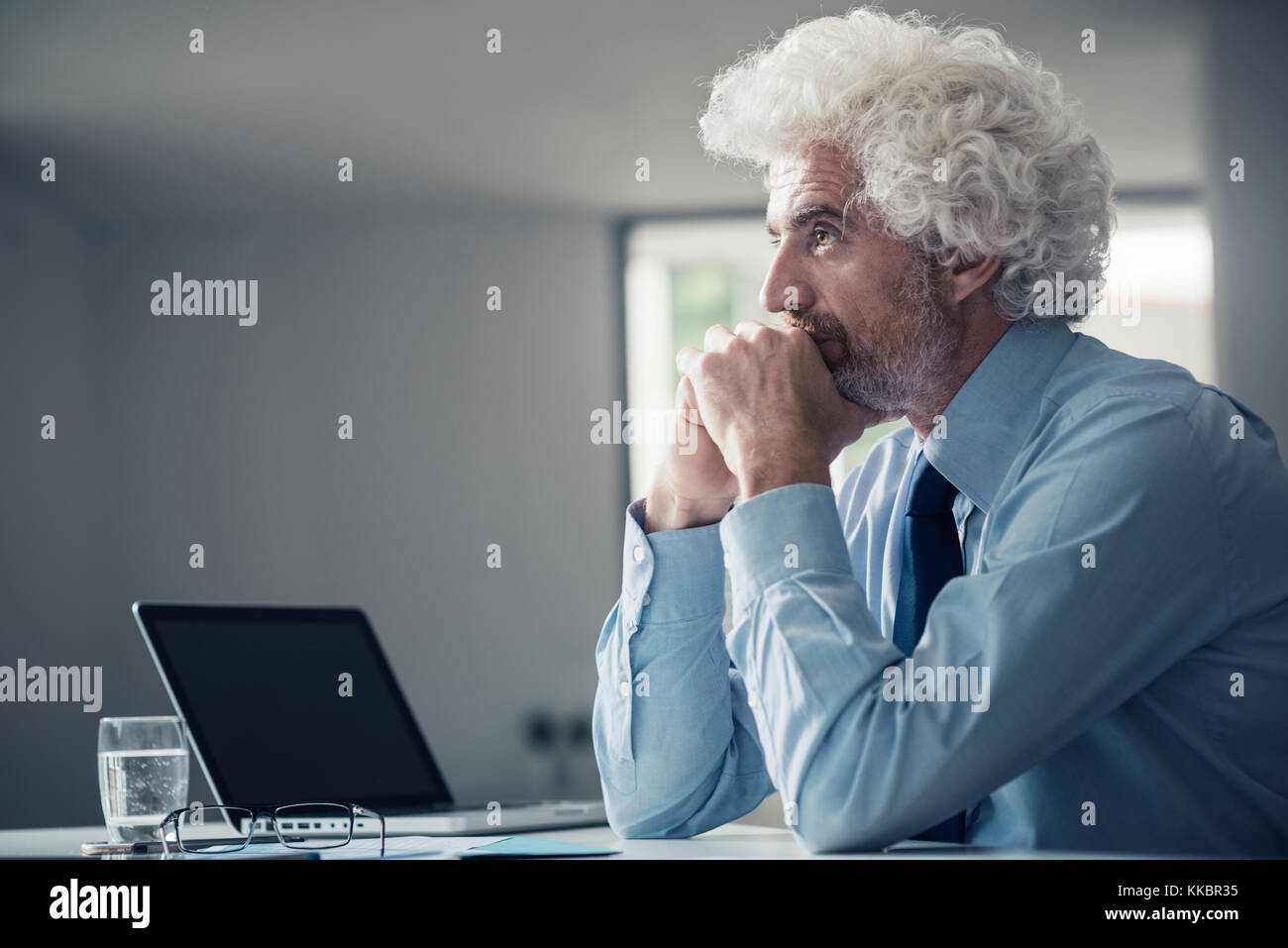 Nachdenklich ernsten Geschäftsmann weg schauen mit der Hand am Kinn, Sitzen im Büro Stockfoto