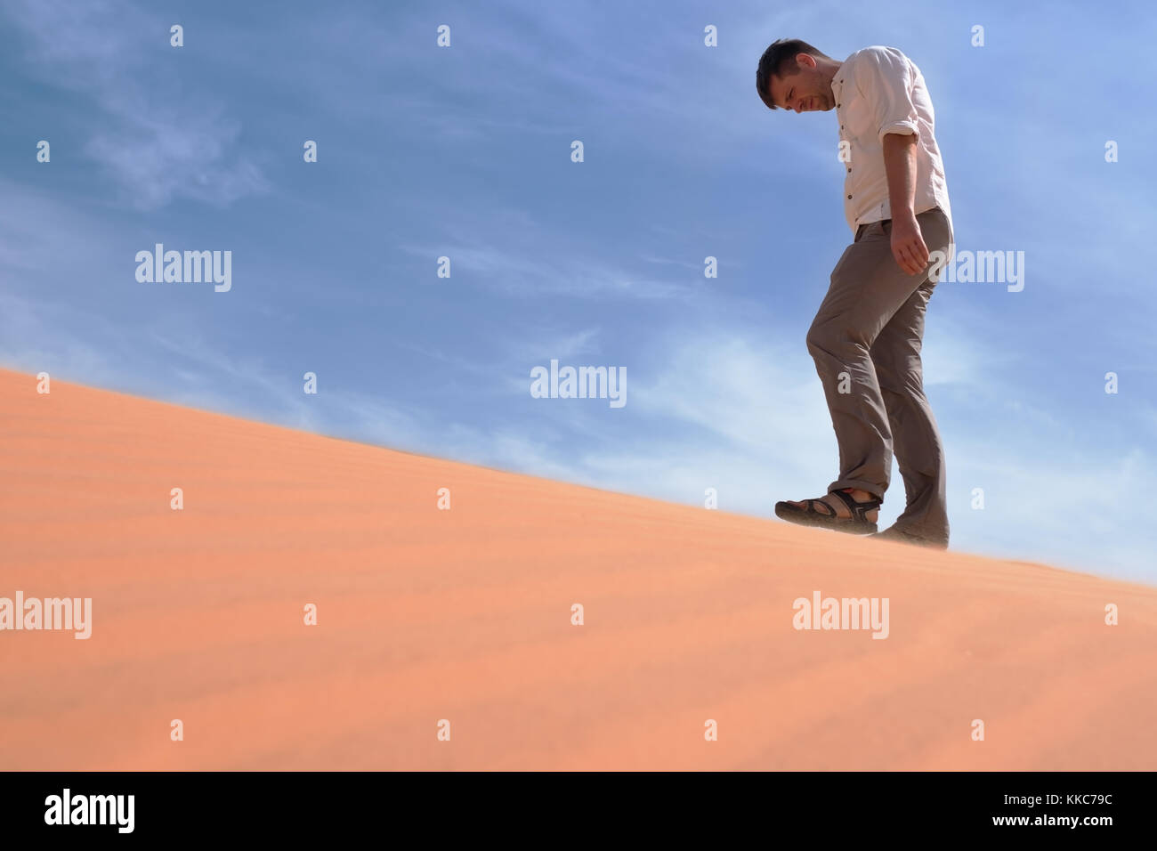 Mann allein zu Fuß in den sonnigen Wüste. Er verloren ist und außer Atem. kein Wasser und Energie. Stockfoto