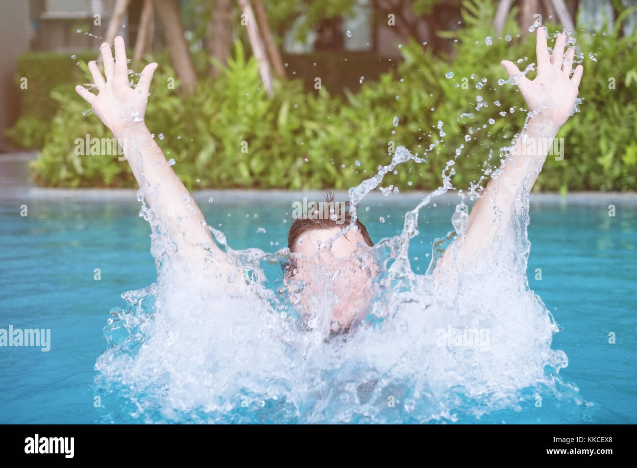 Der Mensch ist Schwimmen und Spielen im Pool mit Spray. Stockfoto