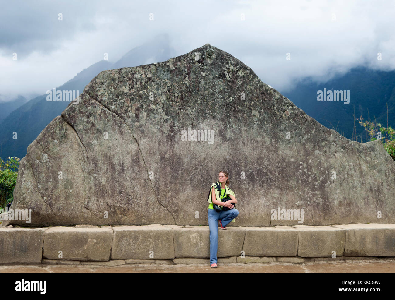 Junge Mädchen und Inka Wand in Machu Picchu. Beispiel für polygonale Mauerwerk. Die berühmten 32 Winkel Stein in der alten Inka Architektur. Beispiel für polygonale Stockfoto