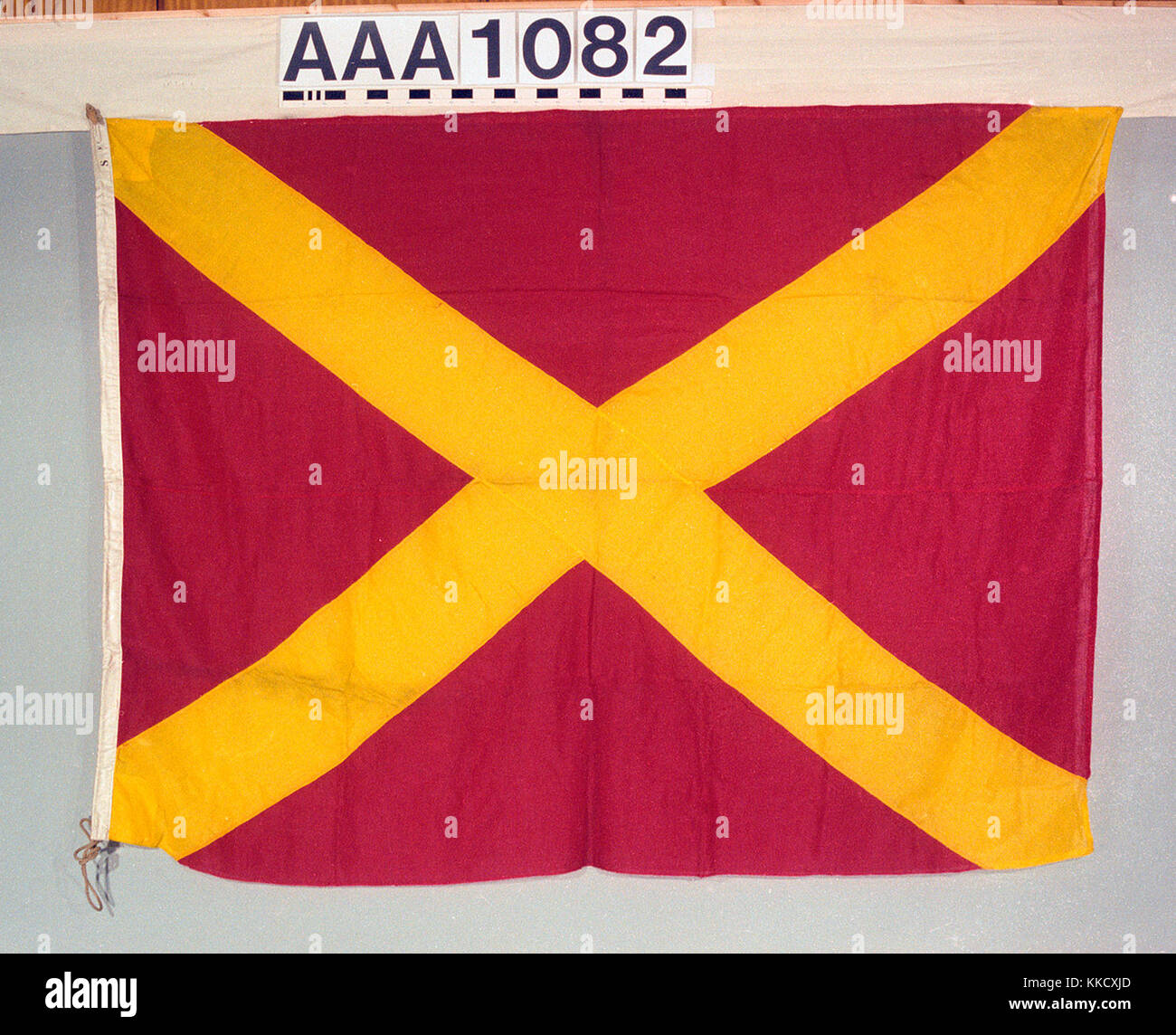 Das Haus Flagge von MacDonald Adams und Co. Die Flagge ist aus Wolle Bunting, Maschine genäht mit einem leinen Hoist. Ein Seil und Holz- toggle ist beigefügt. Auf der Hoist bezeichnet: "8 FT". Eine rechteckige rote Flagge mit einem gelben saltire insgesamt. AAA 1082 Haus Flagge, MacDonald Adams und Co RMG RP -73-30 EIN Stockfoto