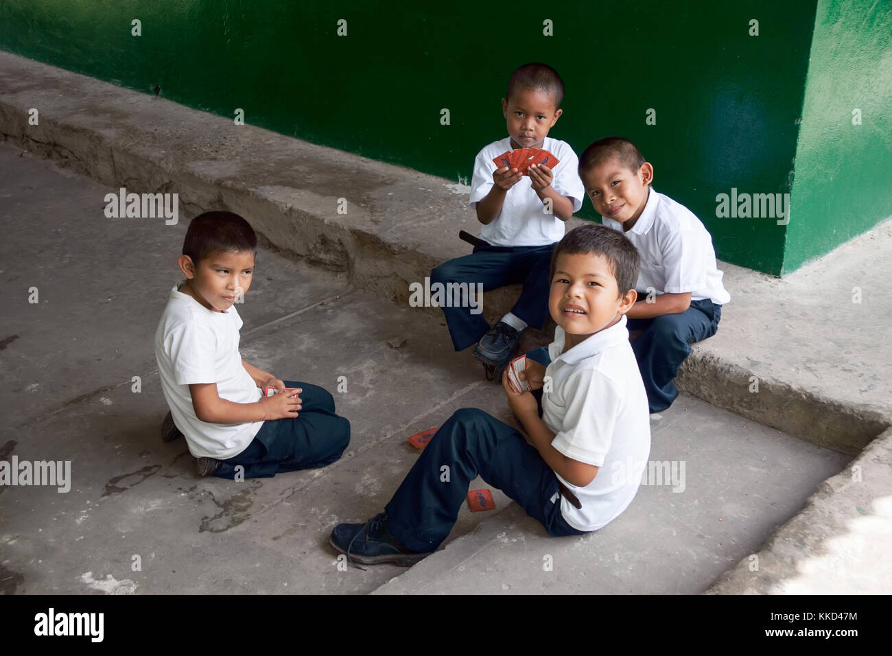 Canaima, Venezuela, 11. November 2010: Jungen in der Schule uniform Karten spielen draußen auf einem dreckigen Betonboden Nest an der Schule an der Wand Stockfoto